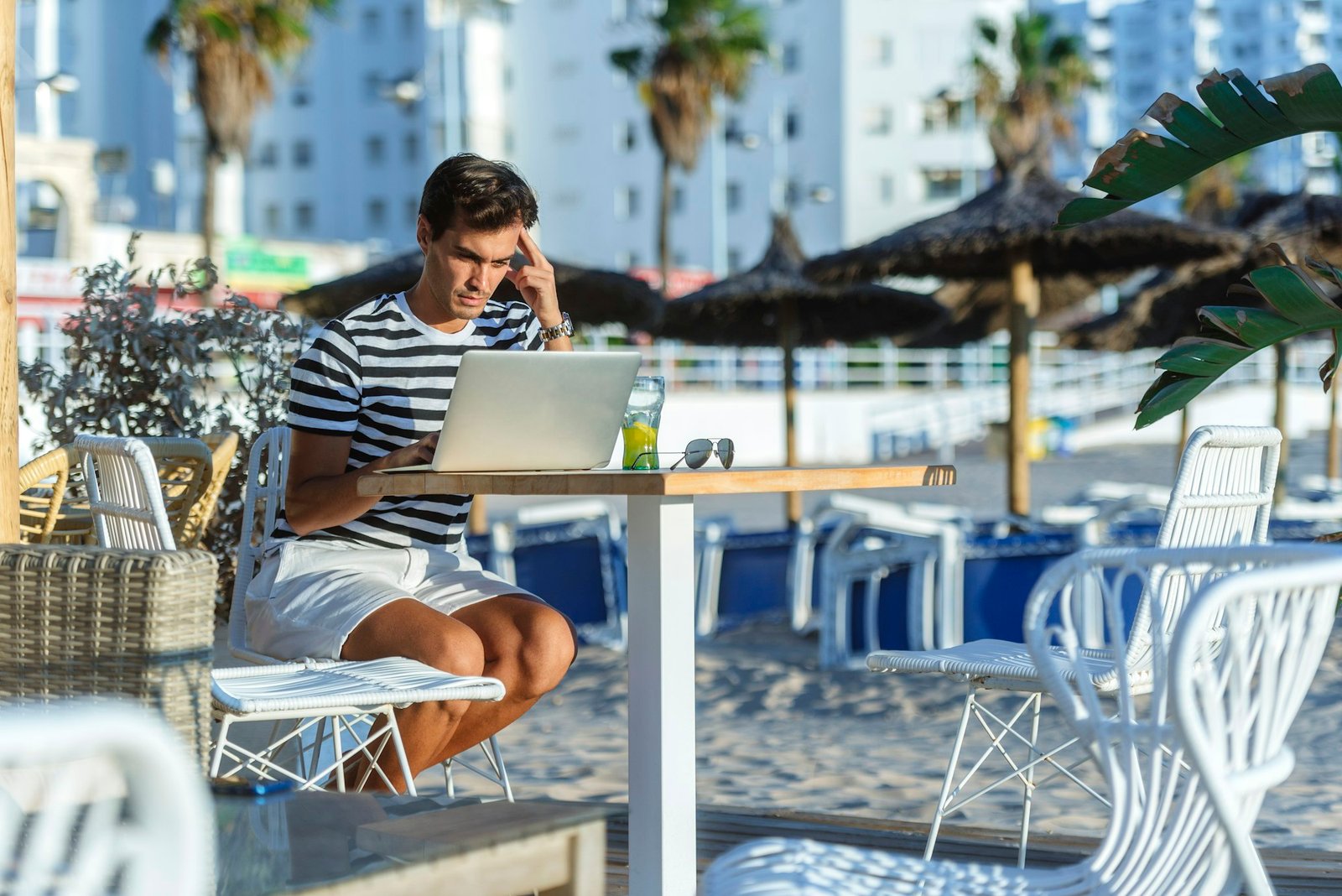 Man with laptop sitting on the terrace of a beach bar